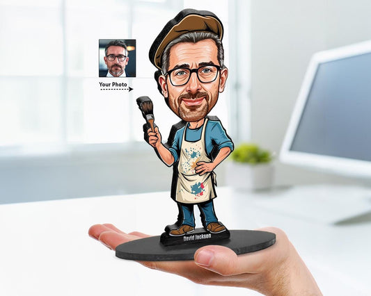 Big-head cartoon caricature of a male painter with apron and brush, custom-made from a photo, printed on clear acrylic or mounted on a wooden base.