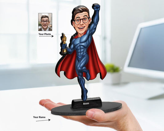 Personalized male superhero caricature figurine with red cape and trophy, based on user's photo. Custom name on base. White background.